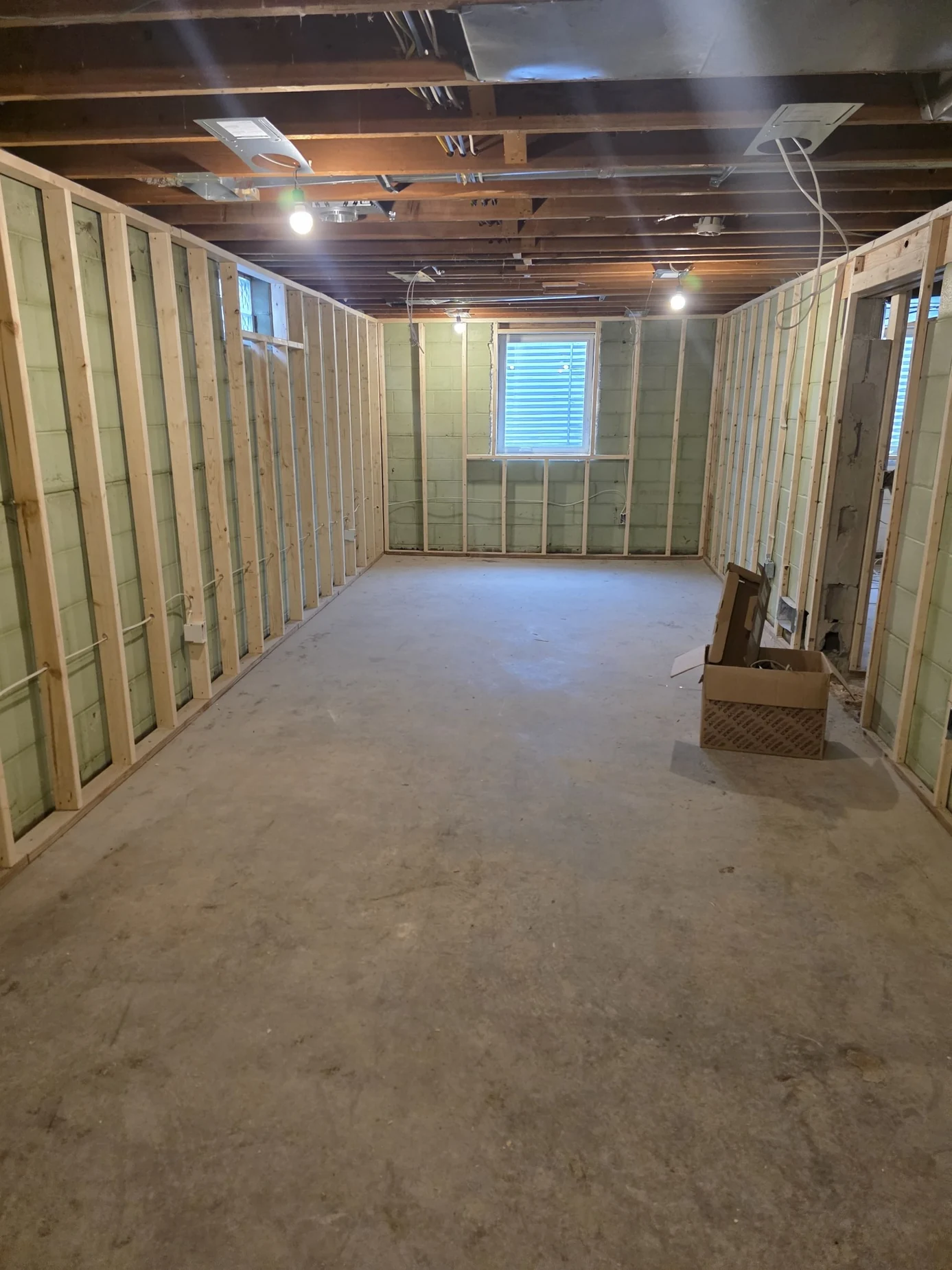 Basement room with unfinished wooden wall framing and central window
