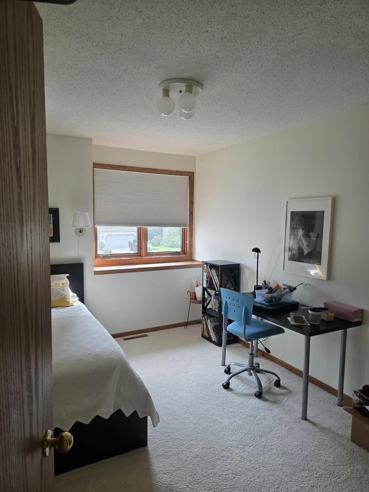 Bright bedroom with freshly finished light-colored walls, bed and desk