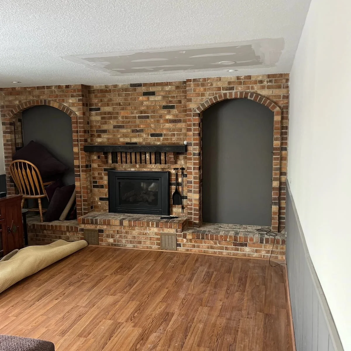 Brick fireplace and visible joint-compound patch on adjacent textured ceiling