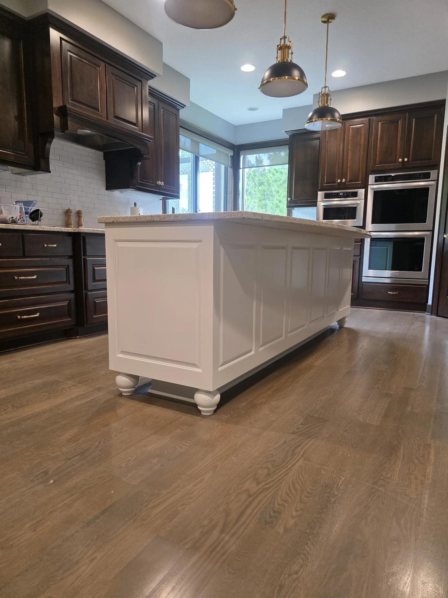 Bright white refinished kitchen island with raised panels and turned feet in completed kitchen