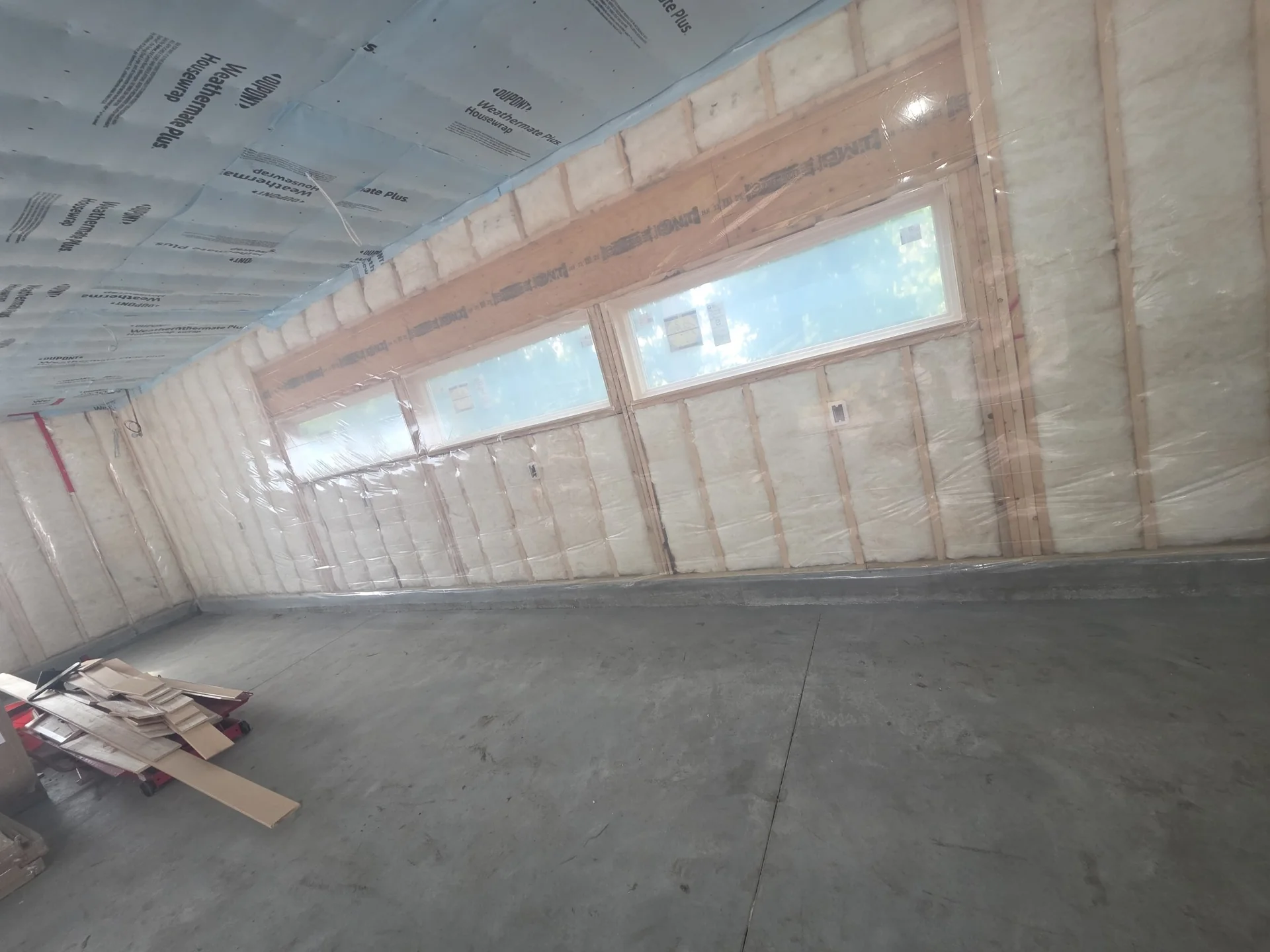 Large interior with exposed wall insulation, taped vapor barrier and narrow horizontal windows