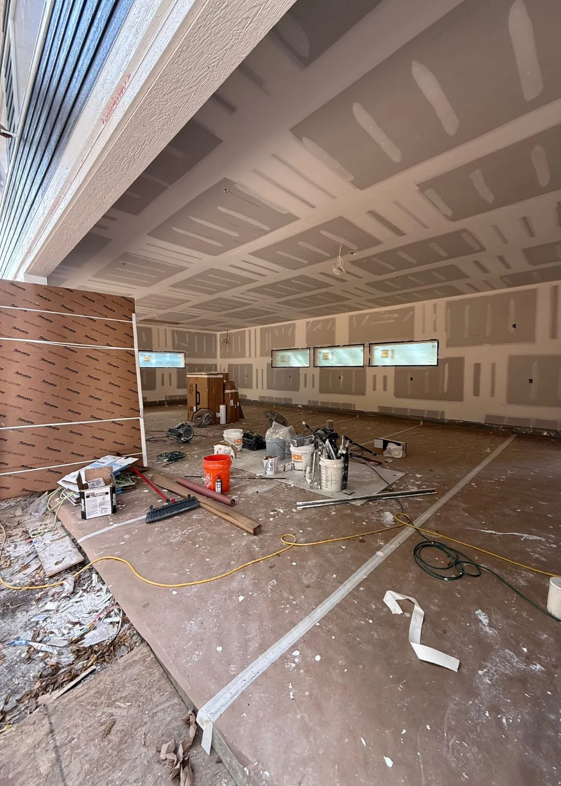 Large room during drywall taping with visible compound on wall and ceiling seams
