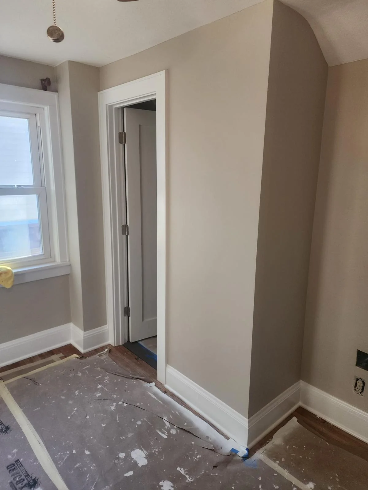 Interior niche with painted walls and white door trim; floors remain protected for ongoing work