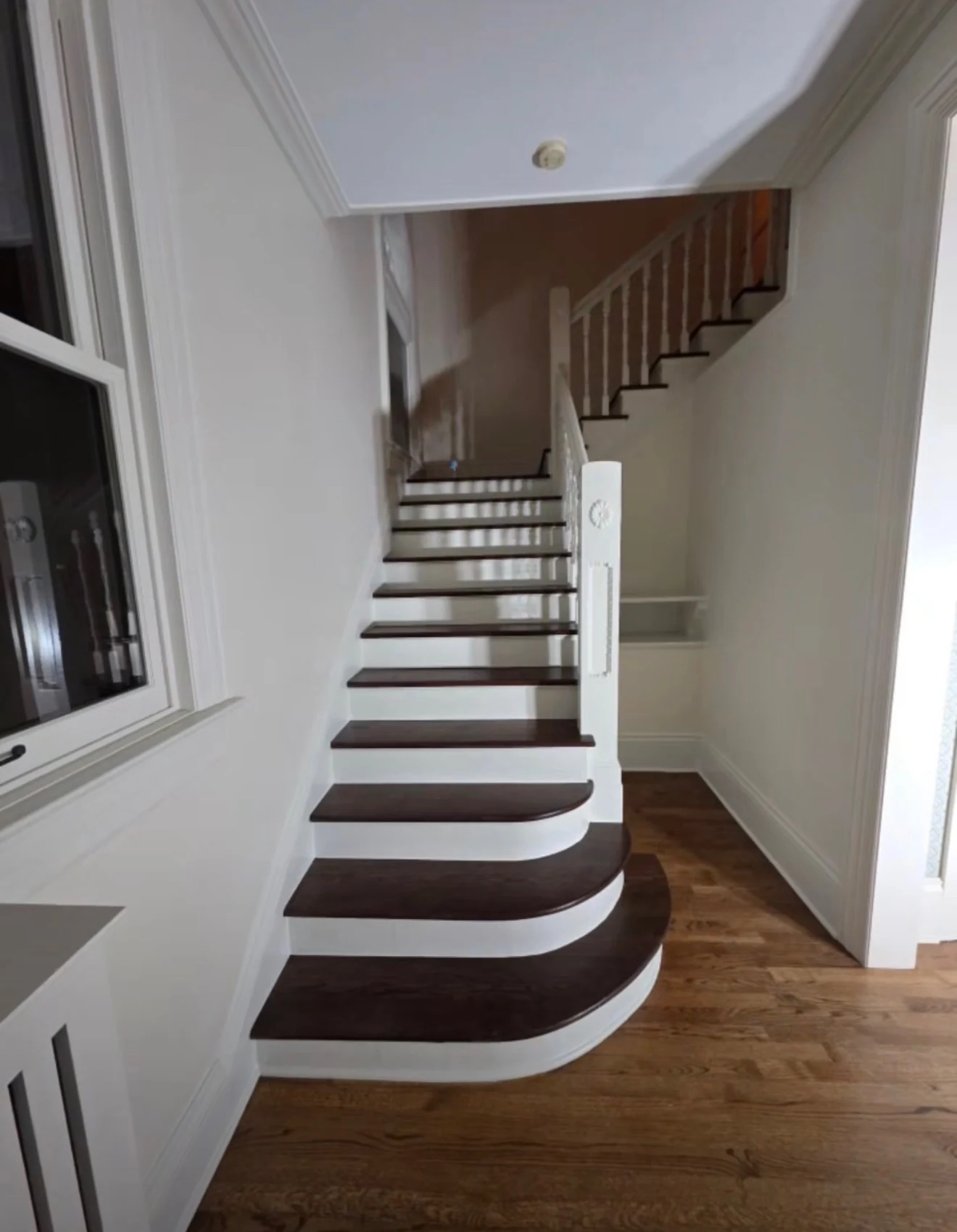 Staircase with dark wood treads, white risers and finished railing
