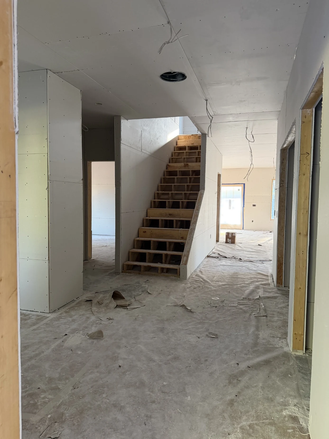 Stairwell at same new-construction site with drywall boards on walls and ceilings