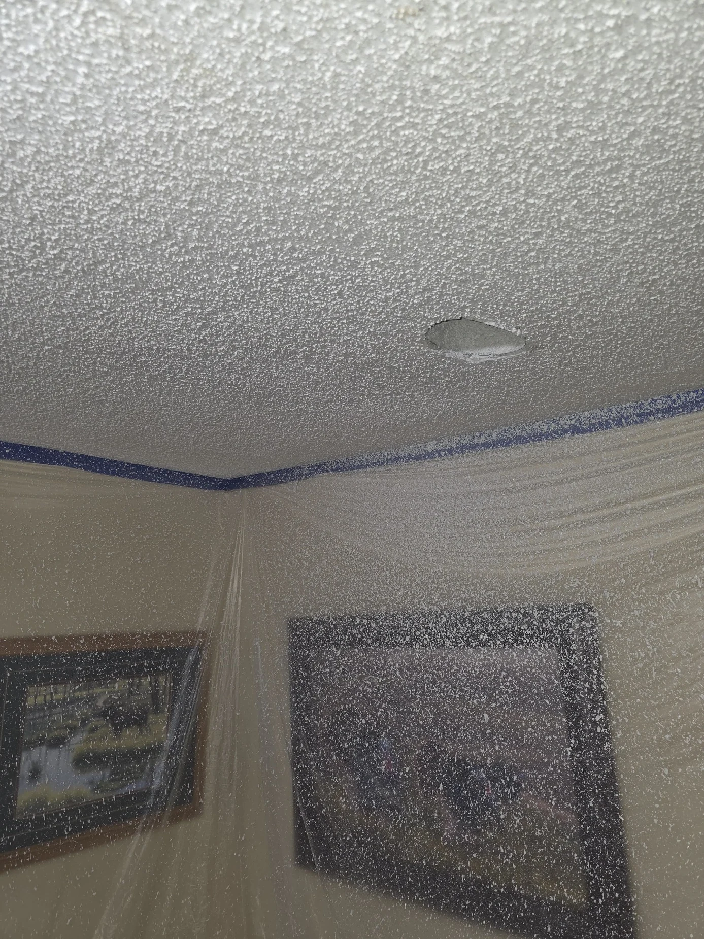 Same room with ceiling patch covered and matching ceiling texture applied; walls and furniture protected