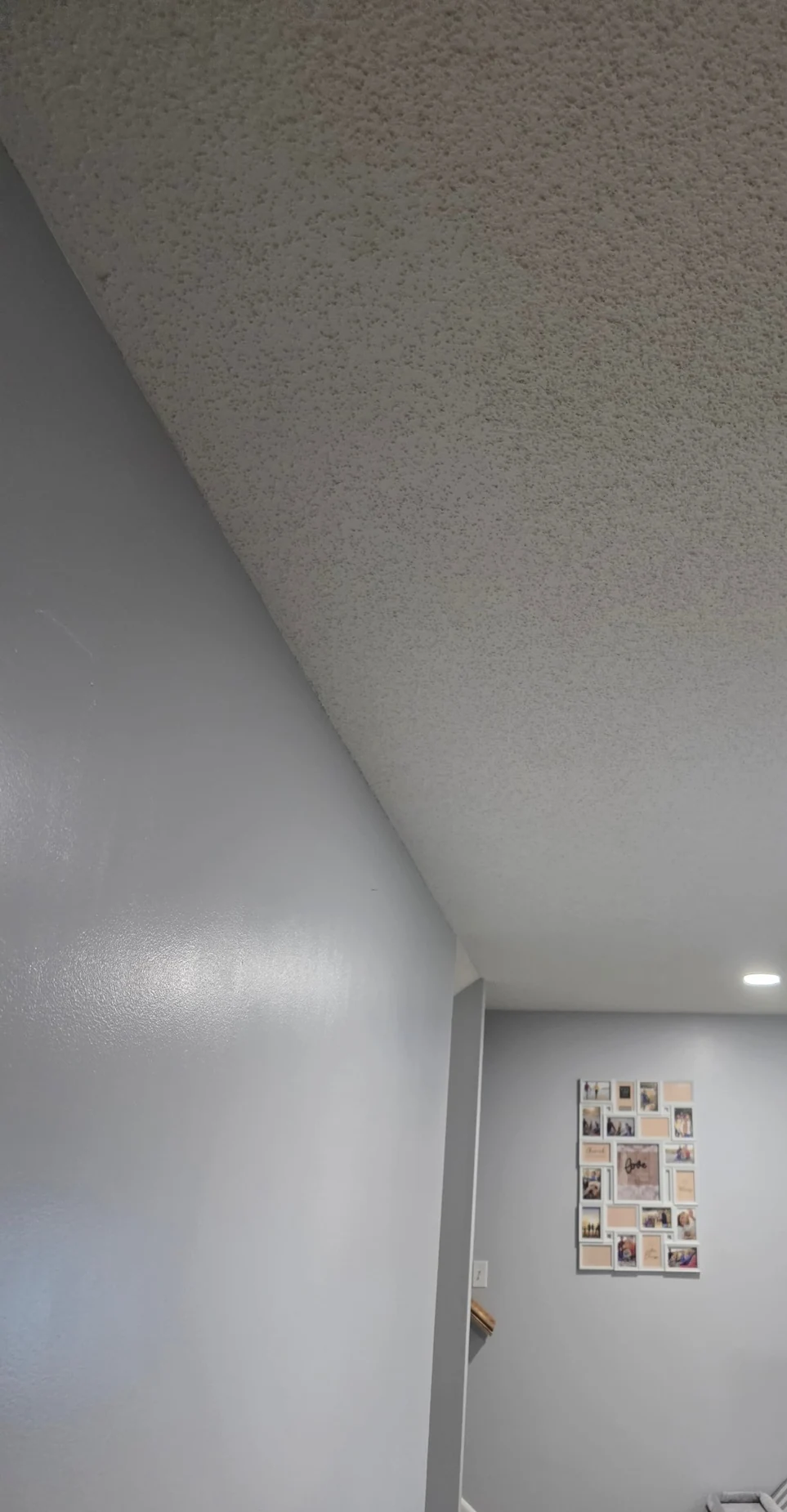 Finished textured ceiling above painted gray interior walls and framed photos