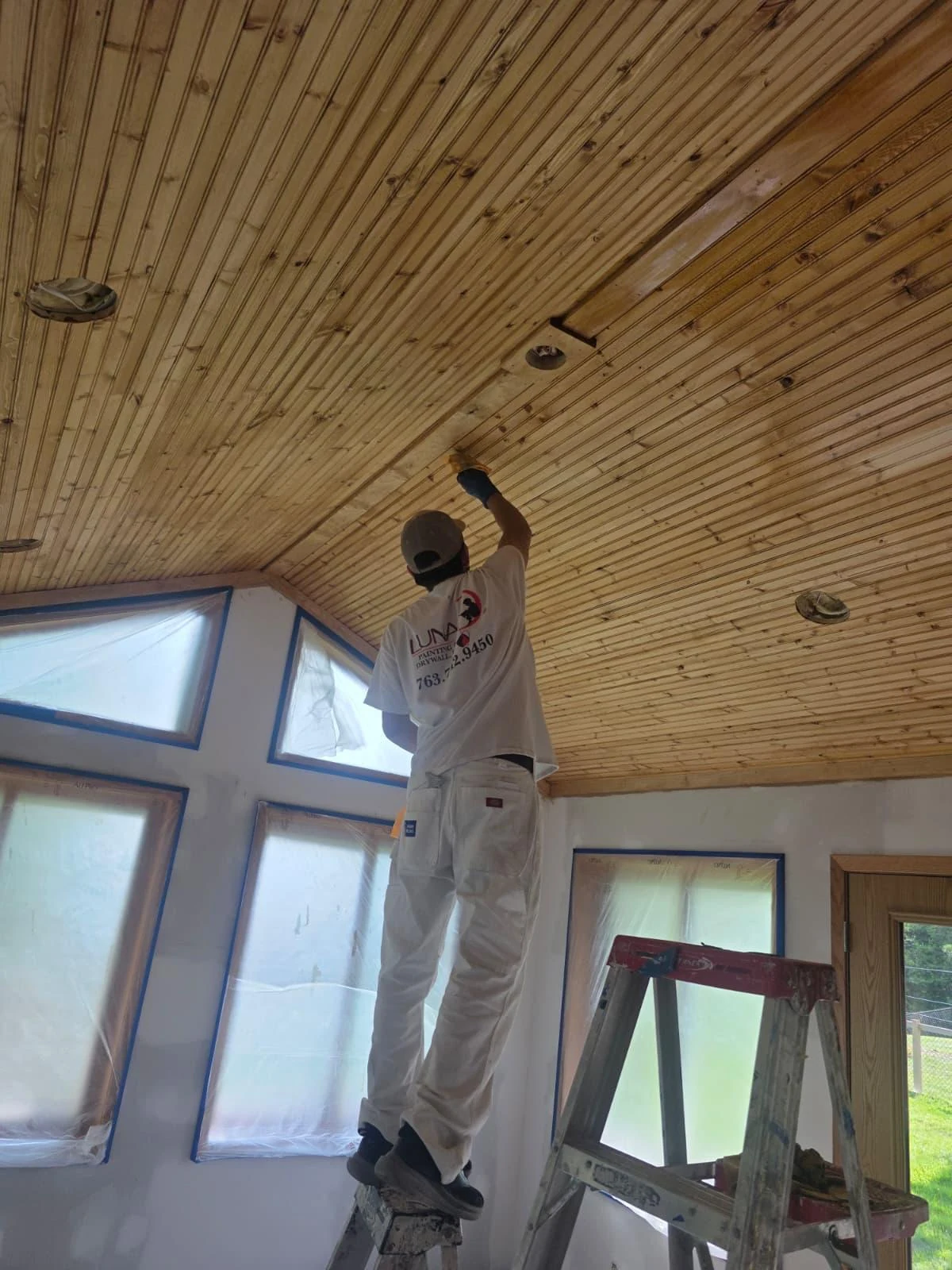 Craftsperson installing individual wooden boards on a vaulted ceiling